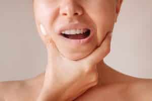 femme se serrant la mâchoire suite à une douleur à la mâchoire